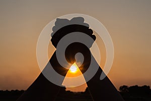 silhouette of couple holding hands up celebrating victory beautiful sunset background,people winning concept