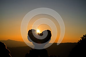 Silhouette of couple holding heart on hill