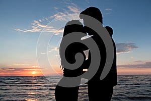 Silhouette of couple kissing at beach during sunset
