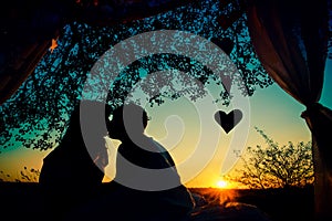 Silhouette of couple in love kissing at sunset