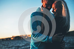 Silhouette of couple in love on the pier, sunset time, water bac