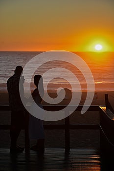 Silhouette of couple in love throwing a fhoto at sunset on the beach