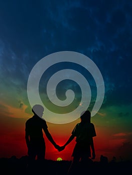 Silhouette couple man and women holding hand and walking together under sunset sky