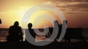 Silhouette Couple of Middle-Aged Man and Woman at Sunset on the Beach by Ocean