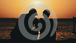 Silhouette Couple of Middle-Aged Man and Woman at Sunset on the Beach by Ocean