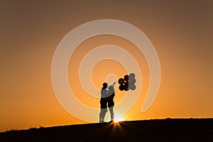 Silhouette of a couple playing with balloons at sunset