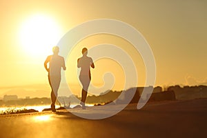 Couple practicing sport running at sunset on the road photo