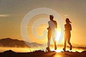 Silhouette of a couple running at sunset