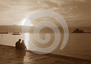 Silhouette of a couple on the seaside promenade at sunset in sepia tone