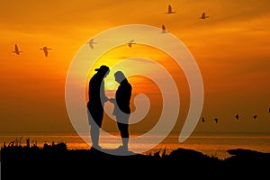 Silhouette couple stand facing each other and promise to take care forever with sun dawn sea scape nature background