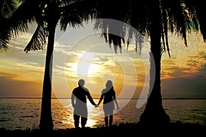 Silhouette couple stand hold hand in front of the sea have coconut tree, look love , so sweet and romantic