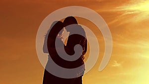 Silhouette of a couple at sunset. Man and woman silhouette in lifestyle sunset slow motion. Couple in love kissing at