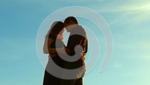 Silhouette of a couple at sunset. Man and woman silhouette in sunset lifestyle slow motion. Couple in love kissing at