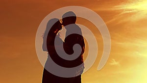 Silhouette of a couple at sunset. Man and woman silhouette in sunset slow motion. Couple lifestyle in love kissing at