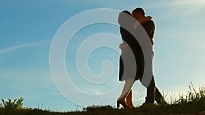 Silhouette of a couple at sunset. Man and woman silhouette in sunset slow motion. Couple in love kissing at sunrise