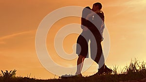 Silhouette of a couple at sunset. Man and woman silhouette in sunset slow motion. Couple in love kissing at sunrise. man