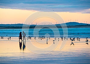 Silhouette of couple walking along the beach at sunset in Essaouira, Morocco