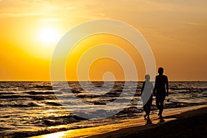 Silhouette of couple walking on the beach.