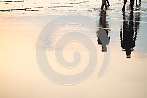 Silhouette of couple walking on beach with drop shadow reflected