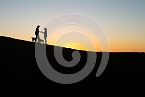 Silhouette of Couple Whit Two Dogs in a Hill at Sunset