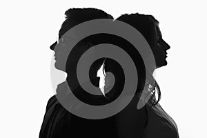 Silhouette of a couple, young girl and a guy leaned against each other head
