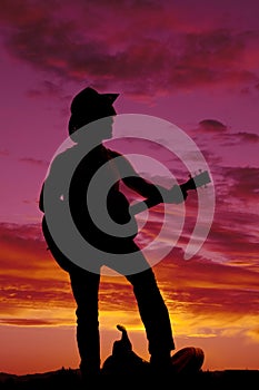 Silhouette of a cowboy foot on saddle playing guitar