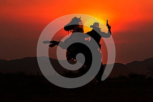Silhouette of cowboy on horseback and sunset