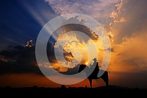 The silhouette of a cowboy on horseback at sunset on  background