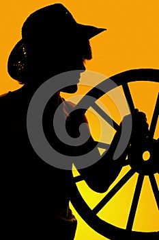Silhouette of a cowboy and wagon wheel in hand