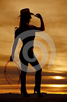 Silhouette cowgirl hold rope touch hat photo