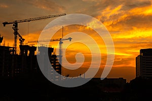 Silhouette of crane and building construction site at sunset