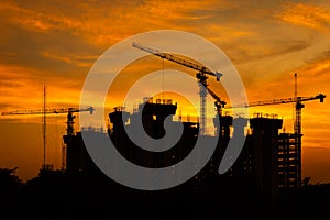 Silhouette of crane and building construction site at sunset