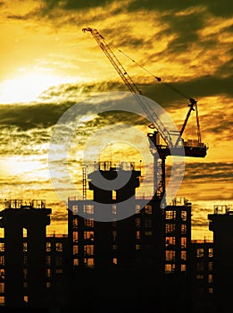Silhouette of crane and building construction and sun set sky wi