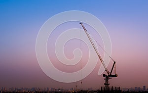 Silhouette crane at the construction site that is working in evening