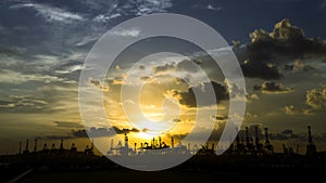 Silhouette of cranes at harbor during sunset.