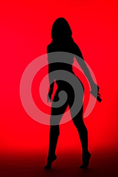 Silhouette of criminal woman in bodysuit holding gun