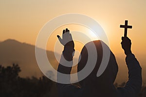 Silhouette the cross in hands, religion symbol in light and landscape over a sunrise, background, religious, faith concept