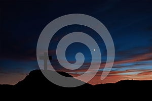 Silhouette of a cross on the mountain at sunrise