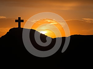 Silhouette of a cross on the mountain at sunrise
