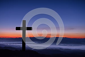 Silhouette of cross on mountain sunrise.