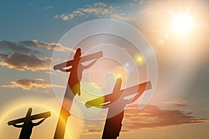 Silhouette of the crucified Jesus Christ on the cross along with other people on background of sunset.