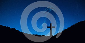 Silhouette of crucifix cross on mountain at night time with hand praying background.