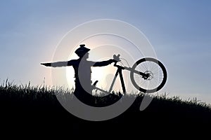 Silhouette of a cyclist with a bike in the sun