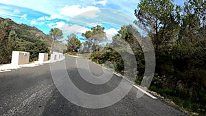 Silhouette of cyclist descending on empty mountain asphalt road at sunny day