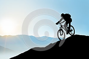 Silhouette of Cyclist Riding the Bike Down the Rock at Sunrise. Extreme Sport and Enduro Biking Concept.