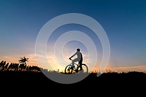 Silhouette of the cyclist riding a Moutain bike at sunset