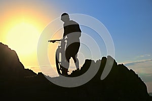 Silhouette Of A Cyclist Standing on Clif Against The Sun