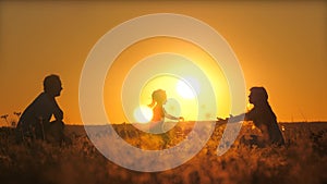 Silhouette of a daddy circling a small child in flight at sunset. Father's day. A daughter with a parent is playing a