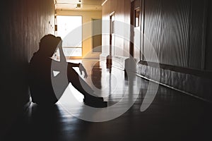 Silhouette of depressed man sitting on walkway of residence building. Sad man, Cry, drama, lonely and unhappy concept