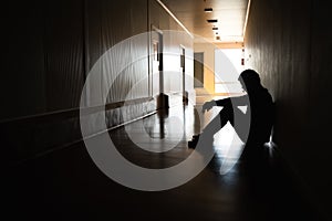 Silhouette of depressed man sitting on walkway of residence building. Sad man, Cry, drama, lonely and unhappy concept